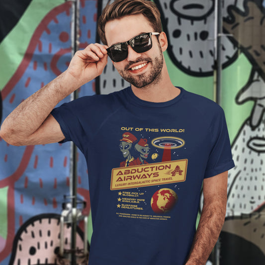 A man wearing a French navy blue graphic t-shirt with a retro alien abduction design, styled with black sunglasses, posing in front of a colourful graffiti wall.