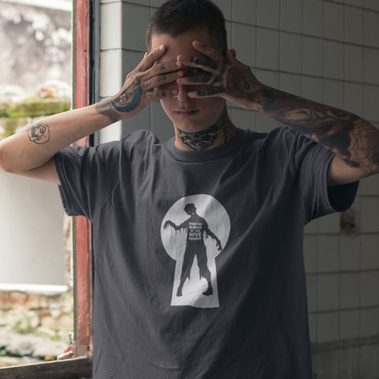 A tattooed man wearing an anthracite grey t-shirt with a zombie through a key hole design with "DON'T BE BLINDED BY THE HIVE MINDED" text.