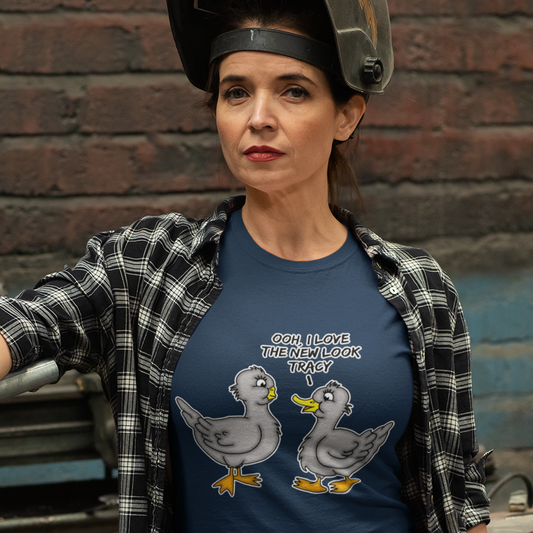 Person wearing a French navy blue t-shirt with cartoon ducks and text, standing against a brick wall. A social issues t shirt design mocking the idea of lip fillers. In a alternative reality are ducks having surgery to make their lips look like humans ? Counterculture cartoon. Made from 100% organic ring-spun cotton, this social awareness t shirt is unisex, high-quality, super comfy, and best of all, eco-friendly.