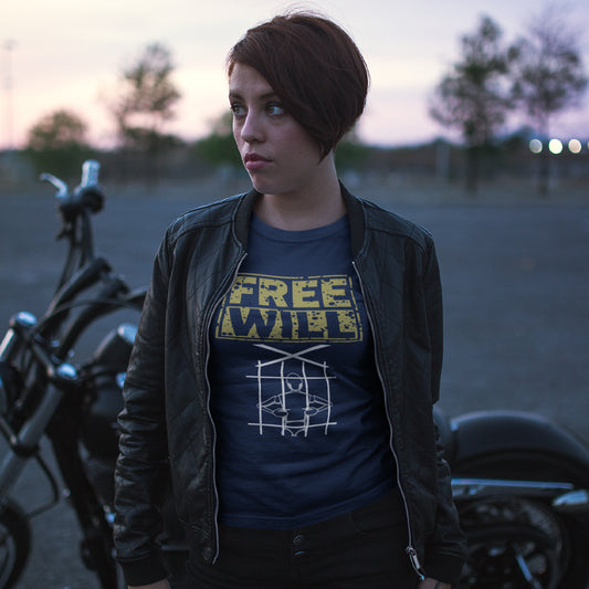 A woman standing in front of a motor cycle wearing a French navy t-shirt with "FREE WILL" text above a puppet in prison.
