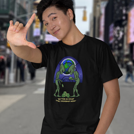 Person wearing a black t-shirt with a graphic design of two green aliens and a planet, standing on a city street. This funny sci fi t shirt is for alien lovers and anti capitalist, and depicts the disappointment of a civilisation now overly obsessed with money and greed. Is it any wonder the aliens have given up on us. Made from 100% organic ring-spun cotton, this anti capitalist t shirt is unisex, high-quality, super comfy, and best of all, eco-friendly.