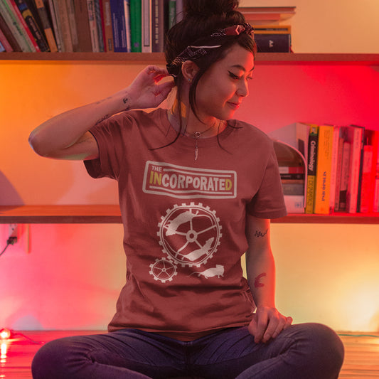 Person wearing a 'The Incorporated' t-shirt in a room with bookshelves. This non conformist t shirt questions the effects of a corporate run society. Have we just created a corporate cult to follow ? A satirical and alternative view of the modern rat race. Made from 100% organic ring-spun cotton, this counter culture t shirt is unisex, high-quality, super comfy, and best of all, eco-friendly.