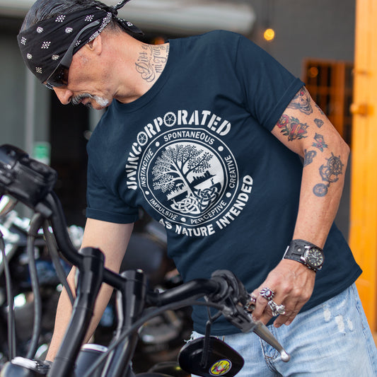 Man wearing an 'unincorporated' t shirt design, standing with a motorcycle. This anti corporate t shirt defines corporations as unnatural and indoctrinating. A design for people who are proud to be a human animal and not programmed into the corporate machine. Urban art using the tree of life as a centre piece. Made from 100% organic ring-spun cotton, this non conformist t shirt is unisex, high-quality, super comfy, and best of all—eco-friendly.
