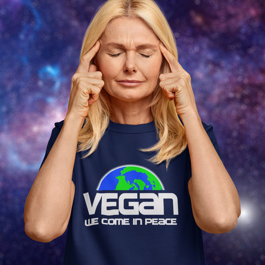 Person wearing a French navy blue t-shirt with 'Vegan We Come in Peace' text and logo on a purple galaxy background. This vegan dairy free t shirt design is for any vegan who feels like they are seen as an alien by others. Reassure people that you are a peaceful creature and want to save the planet. Made from 100% organic ring-spun cotton, this plant based meat free t shirt is unisex, high-quality, super comfy, and best of all, eco-friendly.