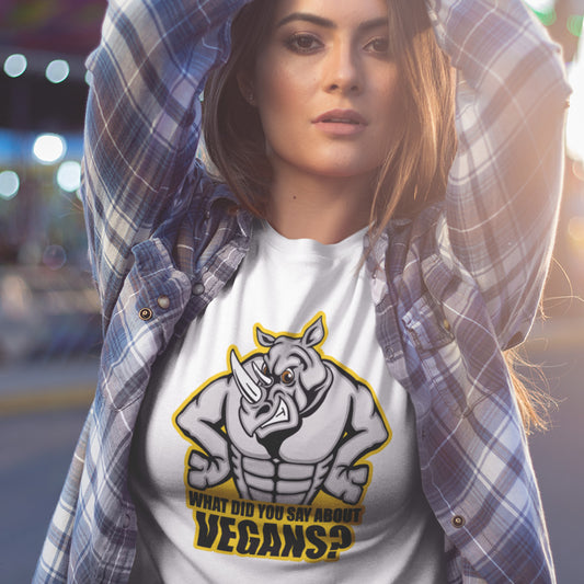 A woman in the street, holding her arms in the air and wearing a white crew neck t-shirt with a cartoon Rhino design and the caption "WHAT DID YOU SAY ABOUT VEGANS?".