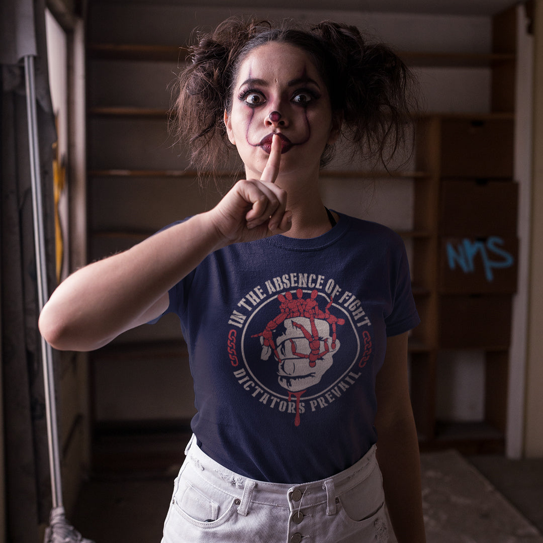 Person wearing a blue t-shirt with graphic design, making a shushing gesture in an indoor setting. This social issues t shirt plays on the saying 'In the absence of light, darkness prevails' with a political message encouraging people to put their apathy and denial aside and fight for their rights before they are taken advantage of. Made from 100% organic ring-spun cotton, this human rights t shirt is unisex, high-quality, super comfy, and best of all, eco-friendly.