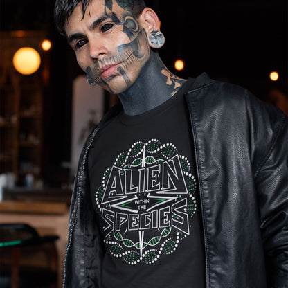 Man wearing a black t-shirt with 'Alien Within the Species' design, standing in a dimly lit room. This non conformist t shirt expands the use of the word 'Alien'. This design is ideal for everyone that feels they don't truly relate to the rest of humankind and modern society. Made from 100% organic ring-spun cotton, this counter culture t-shirt is unisex, high-quality, super comfy, and best of all, eco-friendly.