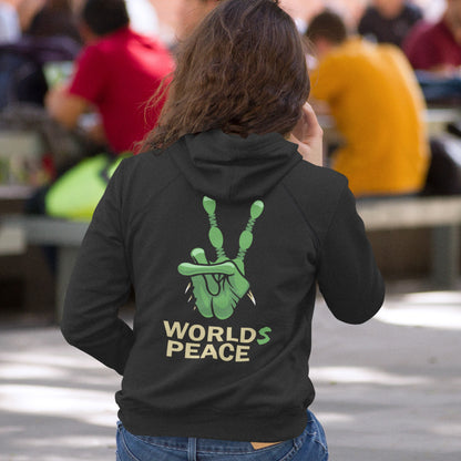 Person wearing a black hoodie with green hand symbol and 'Worlds Peace' text, standing in a casual setting. A world peace hoodie design with an alien lovers twist. When we think of world peace lets not be selfish about it., lets include all Worlds. Comfortable and practical. It's extra soft and has a convenient front pouch pocket. Made from organic cotton and recycled polyester, this funny alien hoodie is the perfect eco-friendly choice.