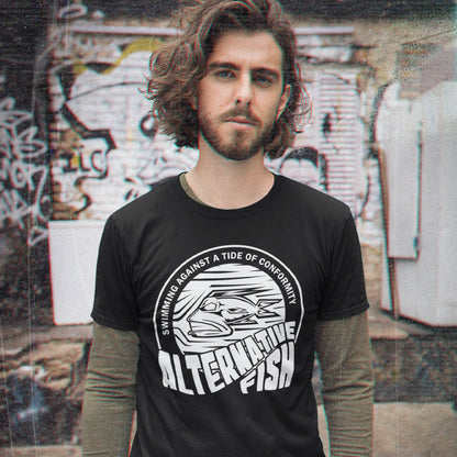 Man wearing a black t-shirt with a graphic design and text, standing in front of a graffiti-covered wall. A non conformist t shirt for all who think outside the box. Don't just be another fish in the sea. Push back the tide of conformity with this anti establishment t shirt design. Made from 100% organic ring-spun cotton, this counter culture t shirt is unisex, high-quality, super comfy, and best of all, eco-friendly.
