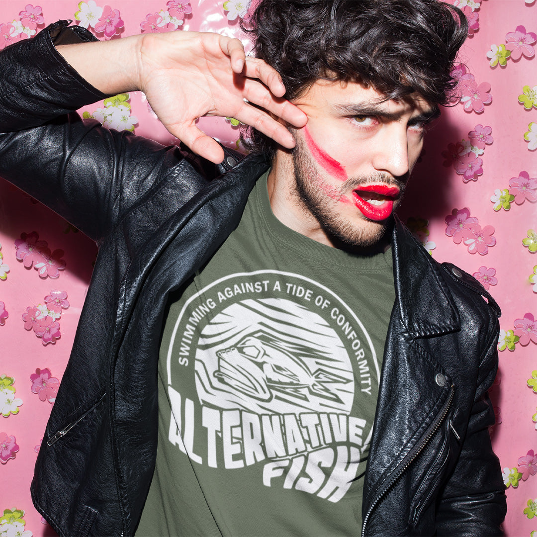 Man wearing a green t-shirt with text and graphics, posing against a pink floral wall. A non conformist t shirt for all who think outside the box. Don't just be another fish in the sea. Push back the tide of conformity with this anti establishment t shirt design. Made from 100% organic ring-spun cotton, this counter culture t shirt is unisex, high-quality, super comfy, and best of all, eco-friendly.