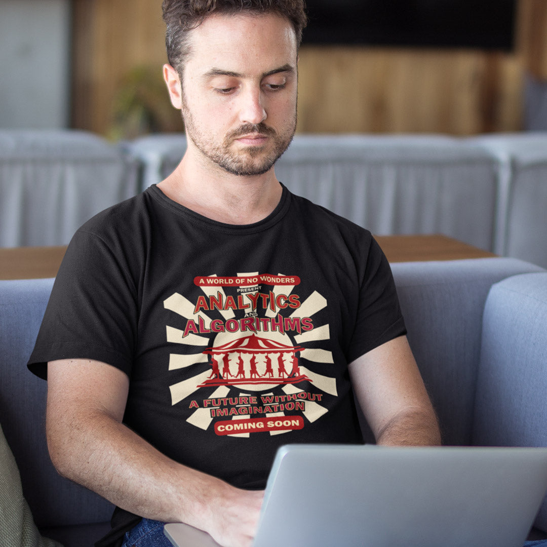 Man on a laptop wearing a black t-shirt with an "AVALYTICS AND ALGORITHMS" spoof fairground poster design.