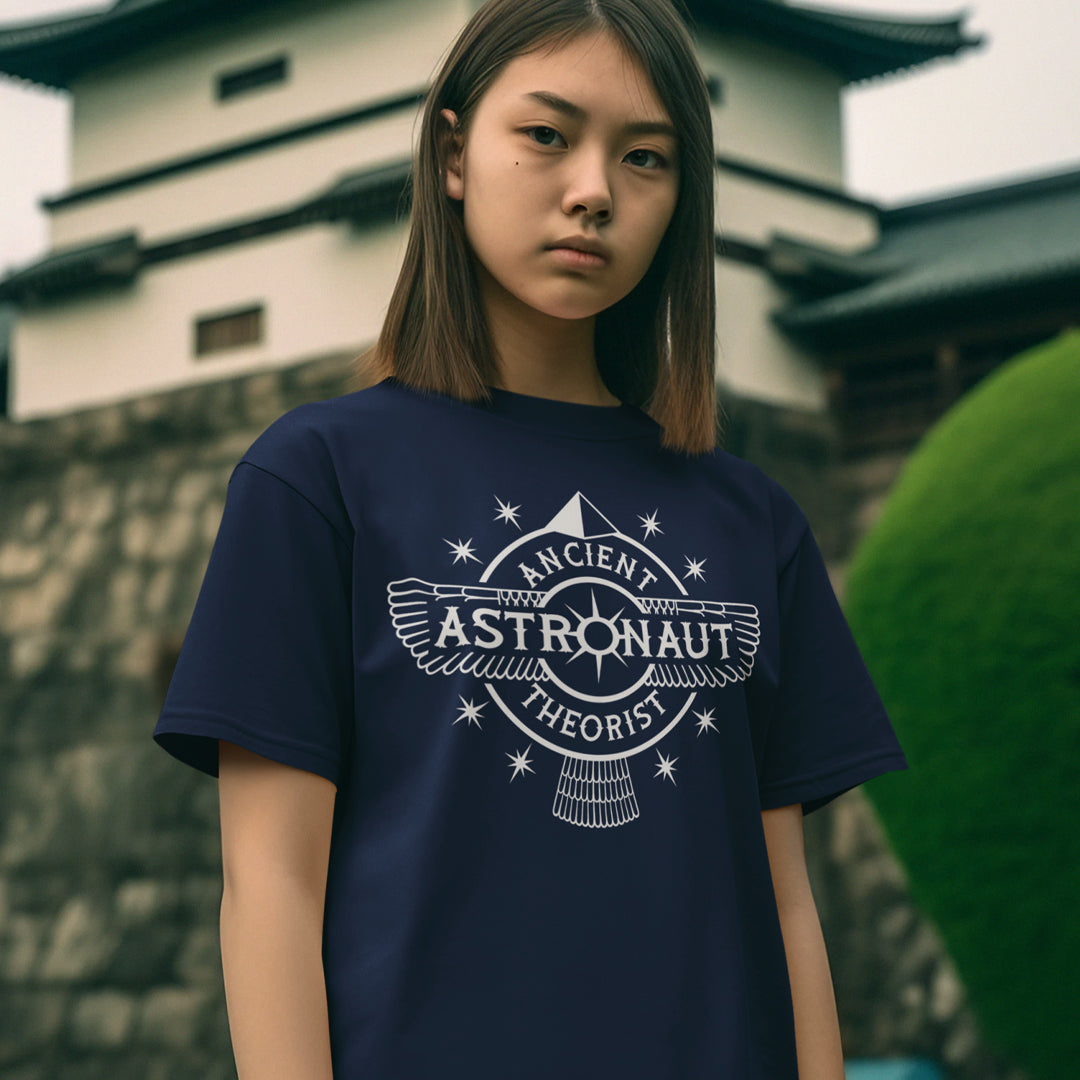 Young woman standing outdoors wearing a French navy blue t-shirt with "ANCIENT ASTRONAUT THEORIST" logo.
