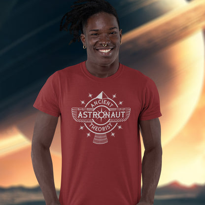 Man standing in front of a large photo of space, wearing a burgundy t-shirt with "ANCIENT ASTRONAUT THEORIST" logo.
