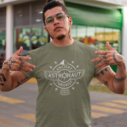 Man standing in the road, wearing a khaki t-shirt with "ANCIENT ASTRONAUT THEORIST" logo.