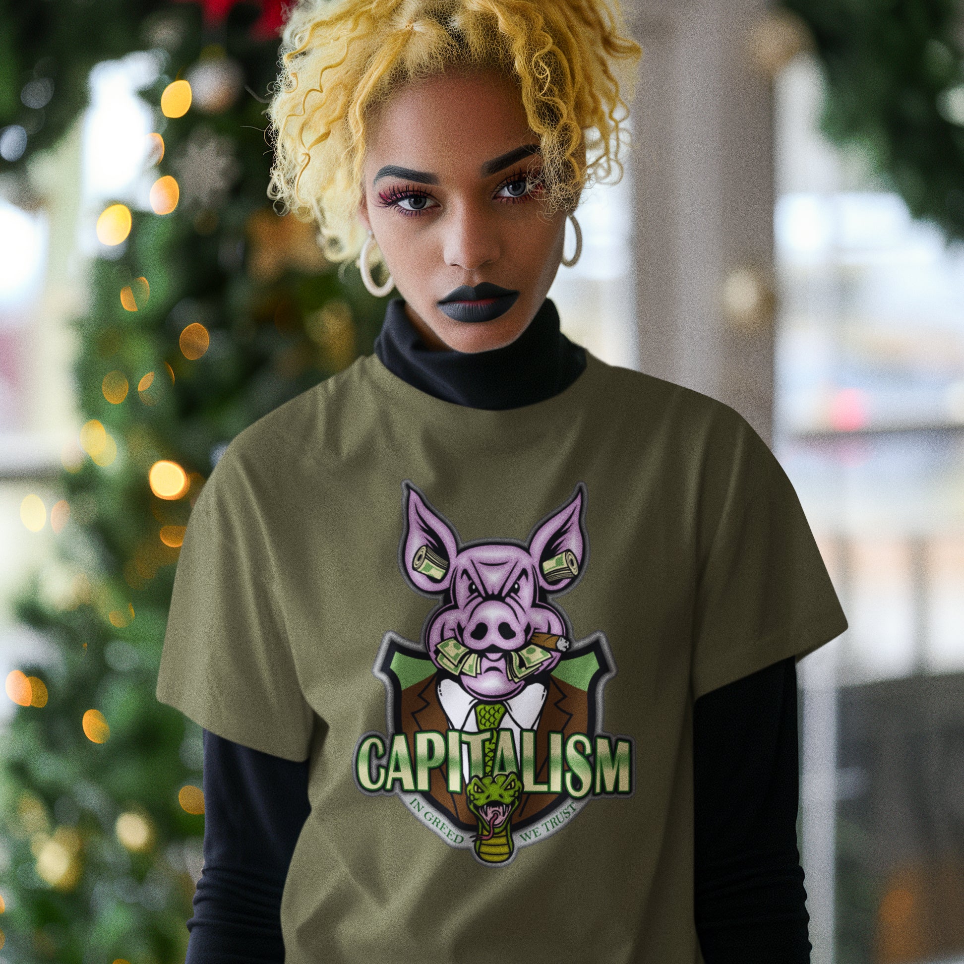 Person wearing a t-shirt with a pig graphic and 'CAPITALISM' text in front of a blurred festive background. An anti-capitalism t-shirt depicting greed and money worship as our downfall. It's greed we worship now, not God. Made from 100% organic ring-spun cotton, this non conformist t shirt is unisex, high-quality, super comfy, and best of all, eco-friendly.