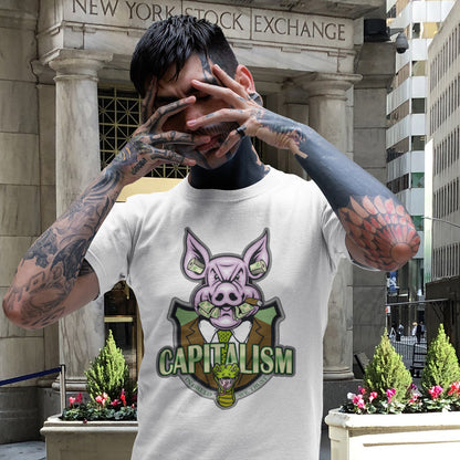 Person wearing a t-shirt with a pig graphic and 'CAPITALISM' text in front of the New York Stock Exchange. An anti-capitalism t-shirt depicting greed and money worship as our downfall. It's greed we worship now, not God. Made from 100% organic ring-spun cotton, this non conformist t shirt is unisex, high-quality, super comfy, and best of all, eco-friendly.