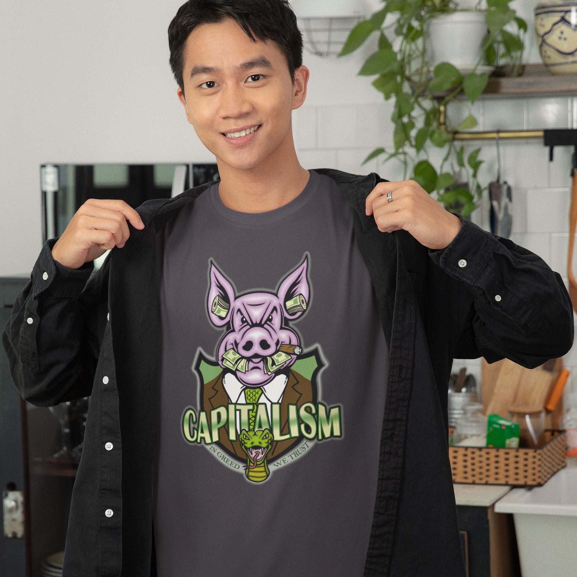 Person wearing a shirt with a pig graphic and 'CAPITALISM' text in a kitchen setting