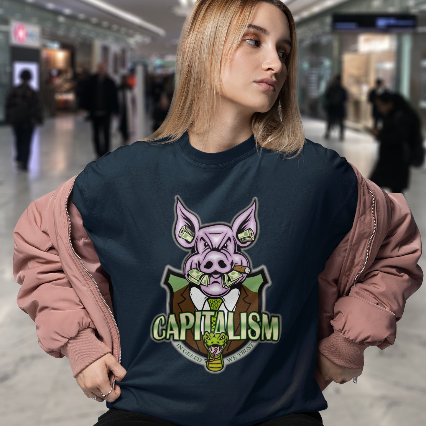 Person wearing a navy blue sweatshirt with a pig graphic and 'CAPITALISM' text in a mall.