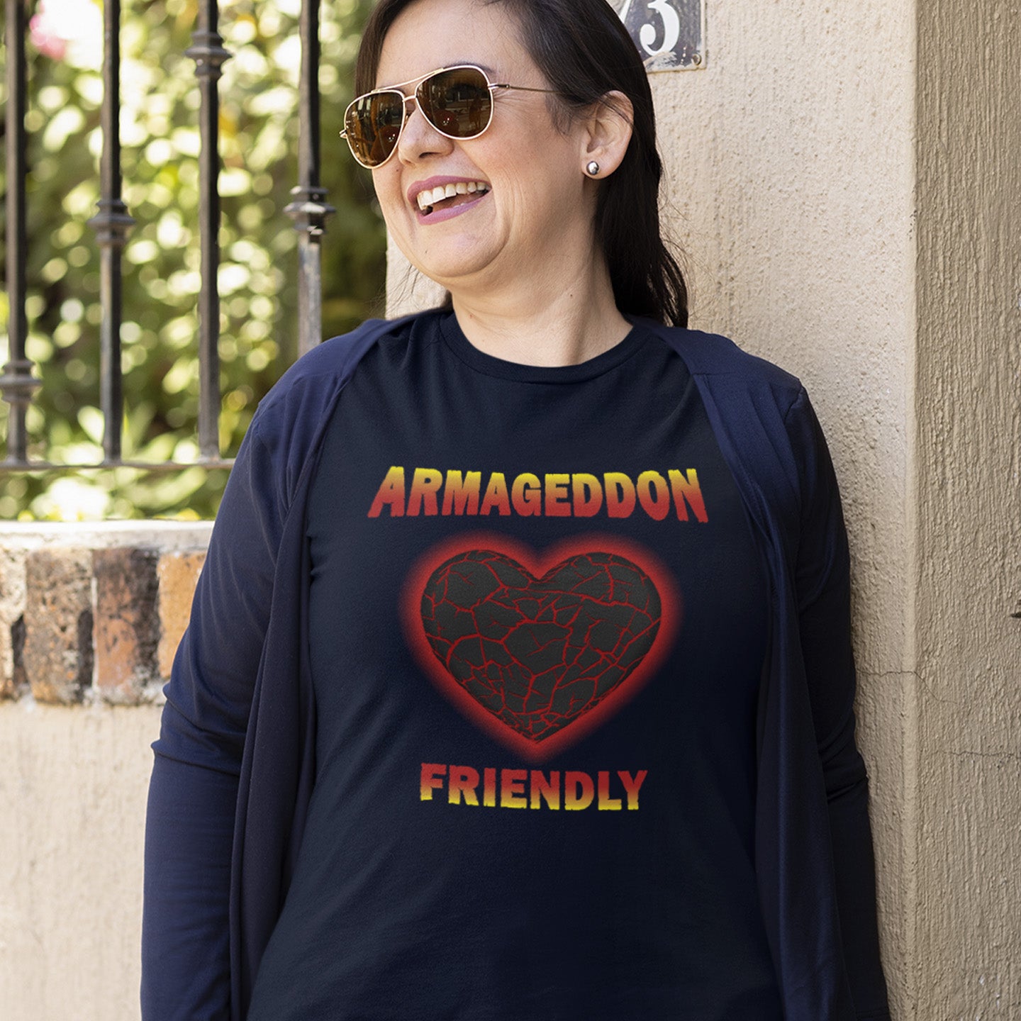 Person wearing a French navy blue shirt with 'Armageddon Friendly' design, standing against a wall. A non conformist t shirt design for the pessimist among us. If you find yourself losing faith in humankind, and feel your heart turning to stone, get it out of your system with this alternative counterculture design. Great for anyone who thinks outside the box. Made from 100% organic ring-spun cotton, this social awareness t shirt is unisex, high-quality, super comfy, and best of all, eco-friendly.