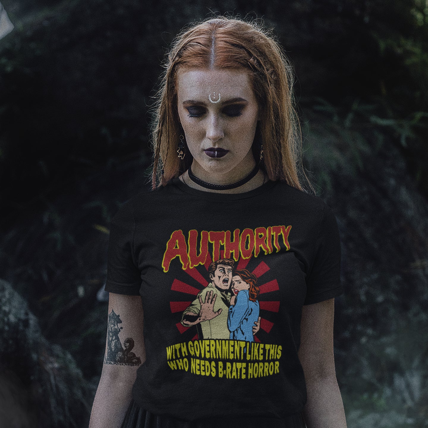 Person wearing a black t-shirt with graphic design and text, standing against a dark background. This non conformist t shirt design is portrayed in an old horror movie poster. A witty but satirical view of just how bad our governance has become and how it resembles watching a B rate horror movie. Made from 100% organic ring-spun cotton, this anti government t shirt is unisex, high-quality, super comfy, and best of all, eco-friendly.