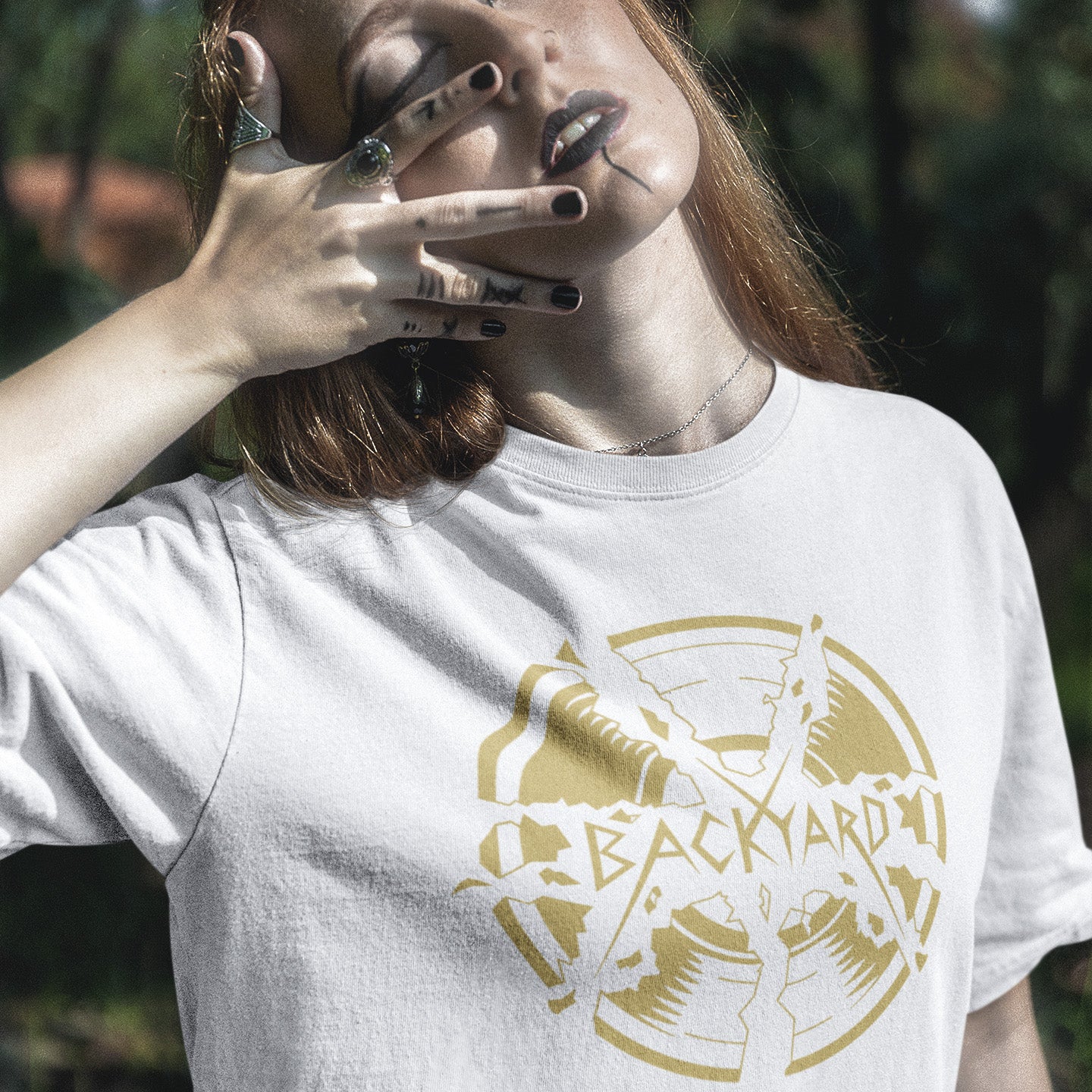 Person wearing a white t-shirt with a gold graphic design outdoors. A unique Backyard t-shirt. If you were there, you were there. If you know, you know and if you remember it you are lucky !! Eco friendly t shirt. Made from 100% organic ring-spun cotton, this nostalgic t-shirt is unisex, high-quality, super comfy, and best of all, eco-friendly.