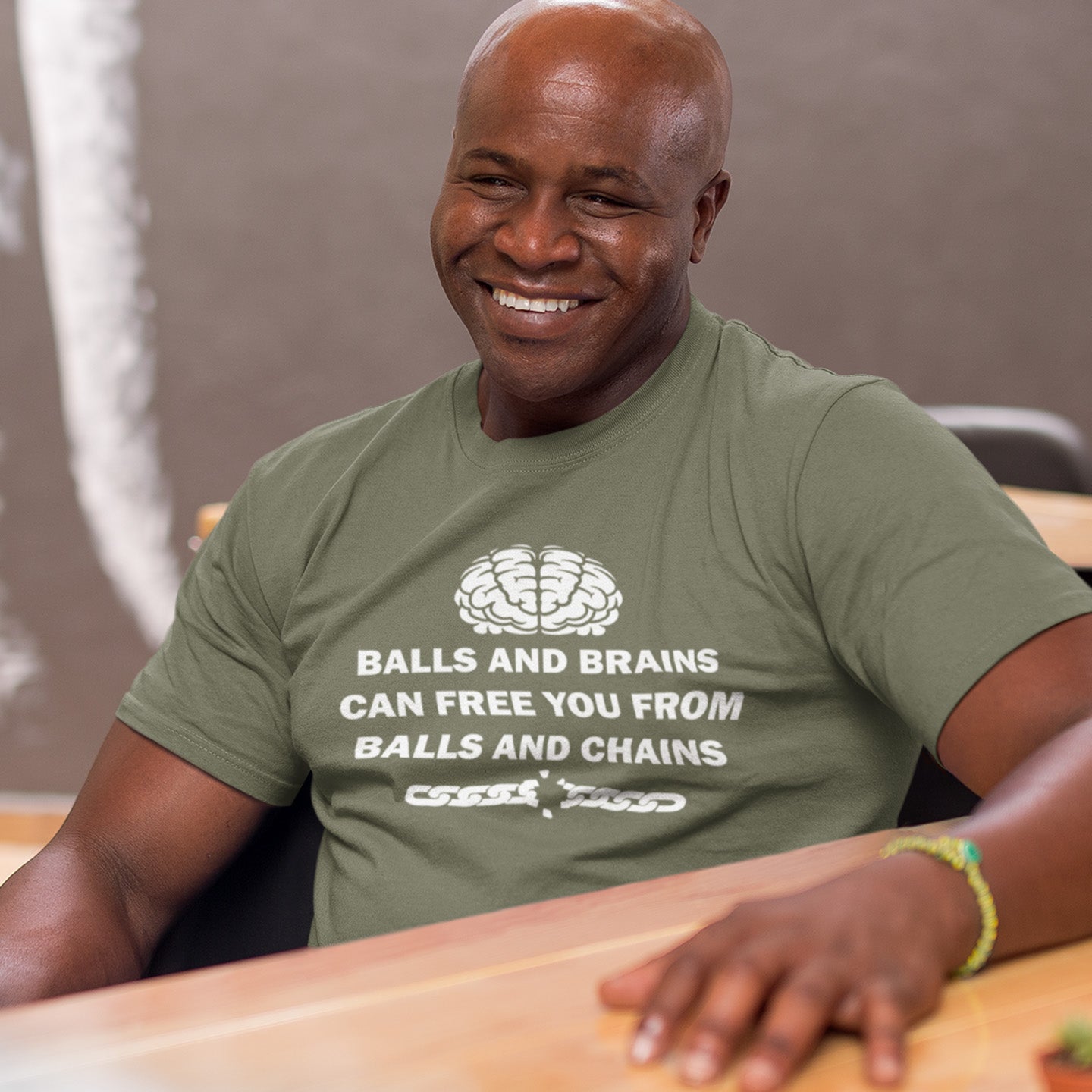 Man wearing a khaki t-shirt with a humorous message, sitting at a table. A civil liberties t shirt limerick to remind you of what it takes to free yourself, metaphorically speaking. Made from 100% organic ring-spun cotton, this self worth t shirt is unisex, high-quality, super comfy, and best of all, eco-friendly.