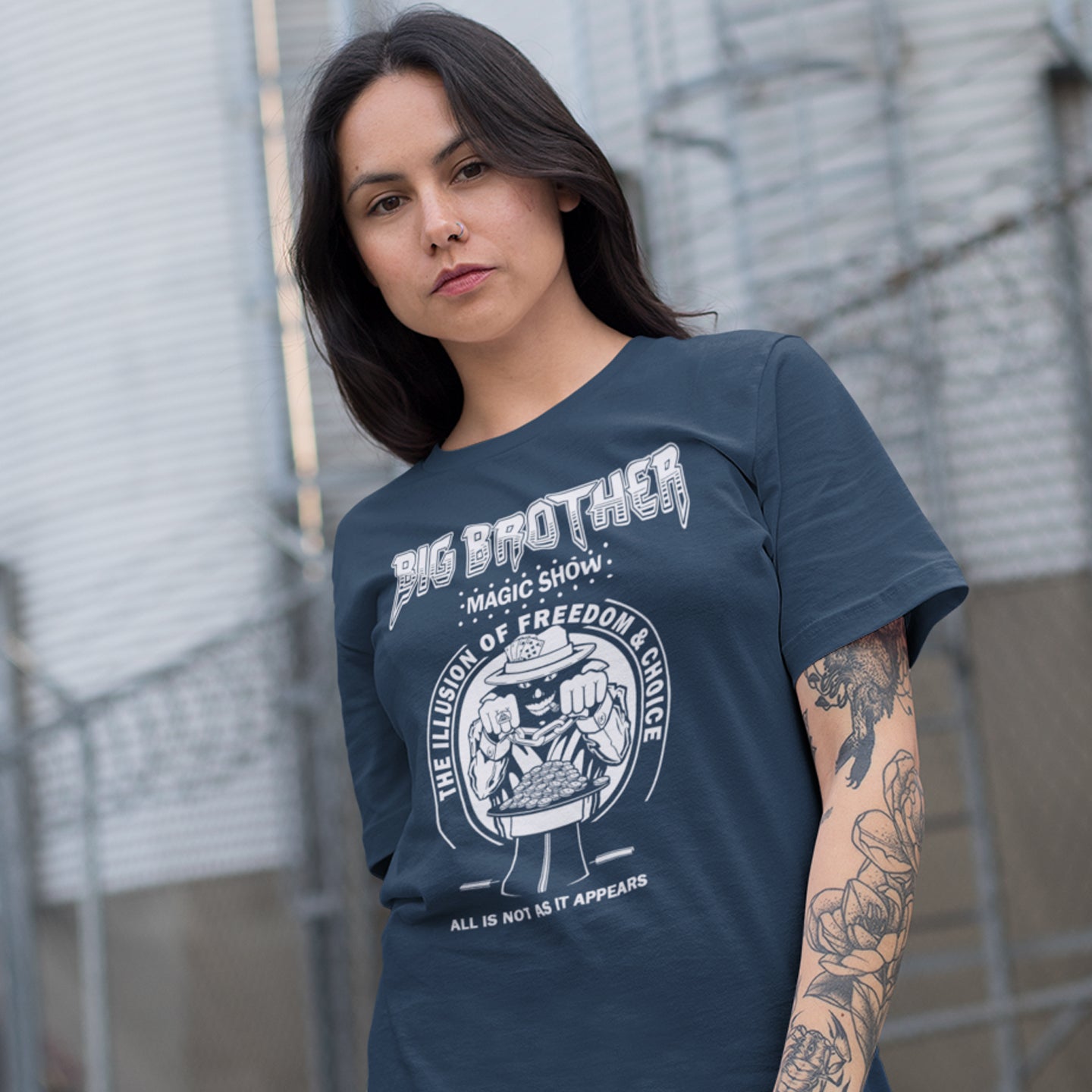 Woman wearing a 'Big Brother' t-shirt with graphic design outdoors. A funny conspiracy theory t-shirt suggesting our 'freedom of choice' is just part of an elaborate illusion. Magic shows are great until you realise you are living in one. This witty unique design hints at our society being distracted by greed. Made from 100% organic ring-spun cotton, this witty conspiracy theory t-shirt is unisex, high-quality, super comfy, and best of all, eco-friendly.