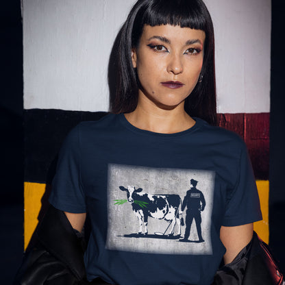 Person wearing a navy blue t-shirt with a graphic design of a cow and a person on a chair. A stencil graffiti t shirt showing the thin line between security and invasion of privacy, highlighted with a touch of satire and sarcasm. Made from 100% organic ring-spun cotton, this urban art t shirt is unisex, high-quality, super comfy, and best of all, eco-friendly.