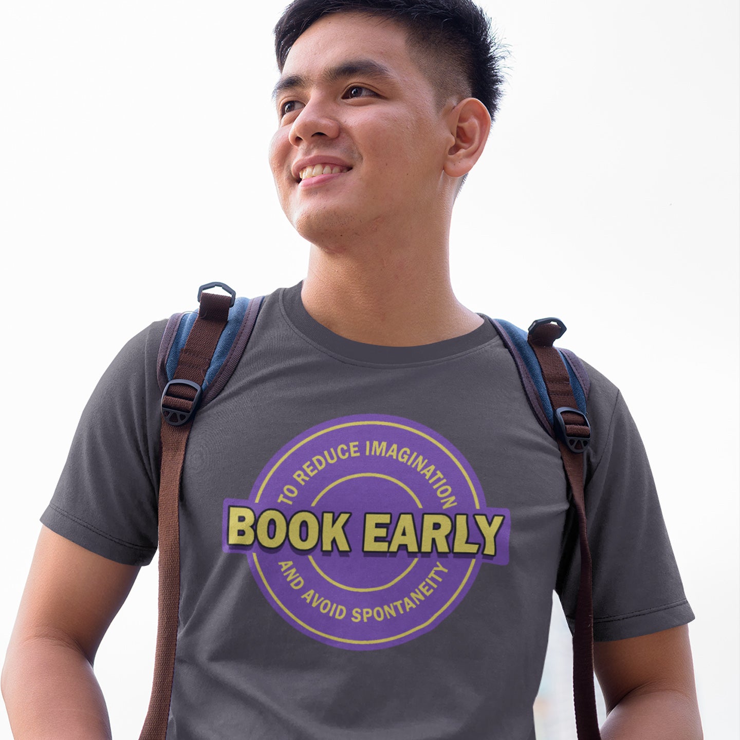 Man wearing anthracite t-shirt with 'Book Early' design and a backpack on a white background. A satirical and sarcastic t-shirt design highlighting the lack of spontaneity and imagination in modern life. The more efficient we make society the more we kill the essence and wonder of life. Made from 100% organic ring-spun cotton, this satirical and sarcastic t-shirt is unisex, high-quality, super comfy, and best of all, eco-friendly.