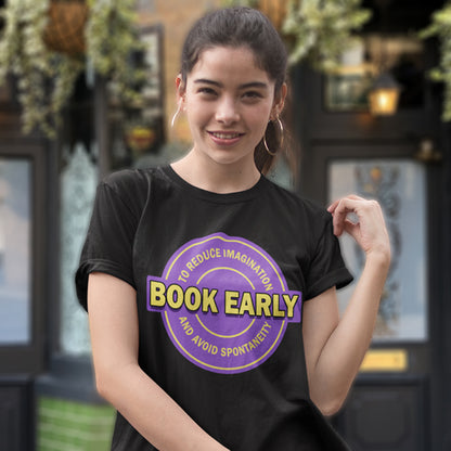 Person wearing a black t-shirt with a purple and yellow graphic design in an outdoor setting. A satirical and sarcastic t-shirt design highlighting the lack of spontaneity and imagination in modern life. The more efficient we make society the more we kill the essence and wonder of life. Made from 100% organic ring-spun cotton, this satirical and sarcastic t-shirt is unisex, high-quality, super comfy, and best of all, eco-friendly.
