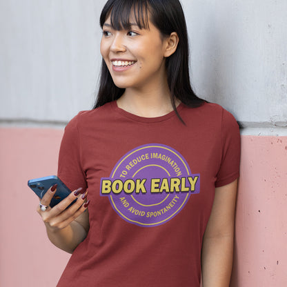 Person wearing a burgundy t-shirt with a purple and yellow graphic and text, holding a phone. A satirical and sarcastic t-shirt design highlighting the lack of spontaneity and imagination in modern life. The more efficient we make society the more we kill the essence and wonder of life. Made from 100% organic ring-spun cotton, this satirical and sarcastic t-shirt is unisex, high-quality, super comfy, and best of all, eco-friendly.
