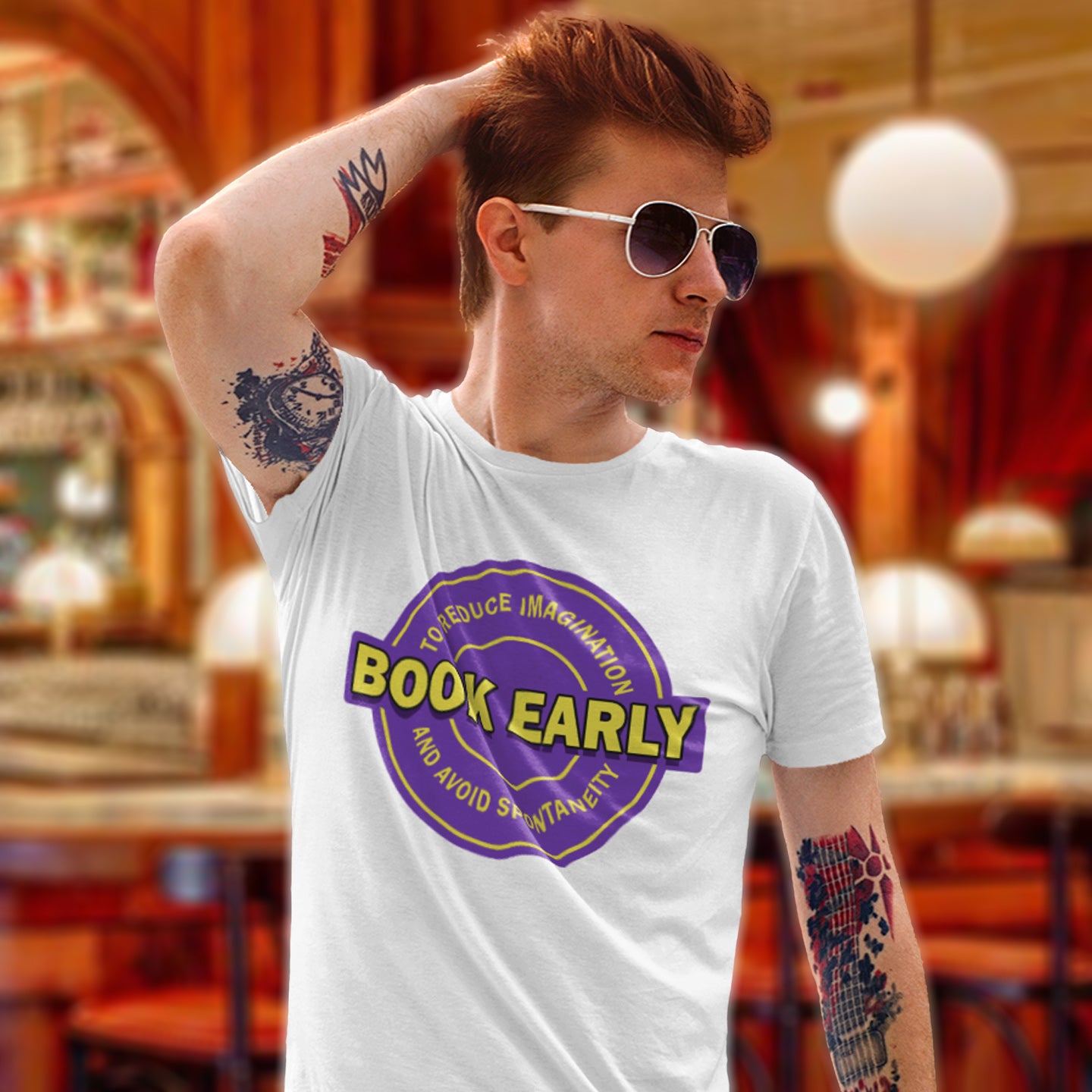 Man wearing a white t-shirt with a purple and yellow graphic design in a restaurant setting. A satirical and sarcastic t-shirt design highlighting the lack of spontaneity and imagination in modern life. The more efficient we make society the more we kill the essence and wonder of life. Made from 100% organic ring-spun cotton, this satirical and sarcastic t-shirt is unisex, high-quality, super comfy, and best of all, eco-friendly.