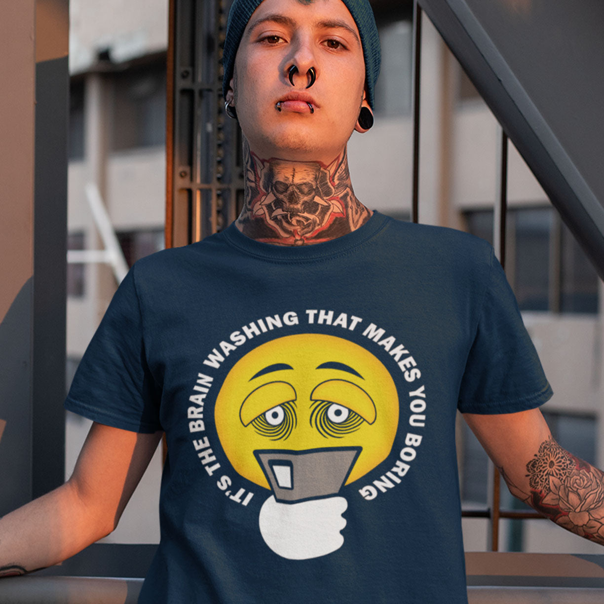 Person wearing a French navy blue t-shirt with a graphic design and text. This conspiracy theorist t shirt highlights the hypnotic obsession some people have with their phone and suggests a conspiracy theory of brain washing as a cause. Ideal for displaying that anti smart phone feeling. Made from 100% organic ring-spun cotton, this conspiracy theory t-shirt is unisex, high-quality, super comfy, and best of all, eco-friendly.