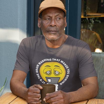 Man wearing a t-shirt with a graphic design, holding a mug outdoors. This conspiracy theorist t shirt highlights the hypnotic obsession some people have with their phone and suggests a conspiracy theory of brain washing as a cause. Ideal for displaying that anti smart phone feeling. Made from 100% organic ring-spun cotton, this conspiracy theory t-shirt is unisex, high-quality, super comfy, and best of all, eco-friendly.