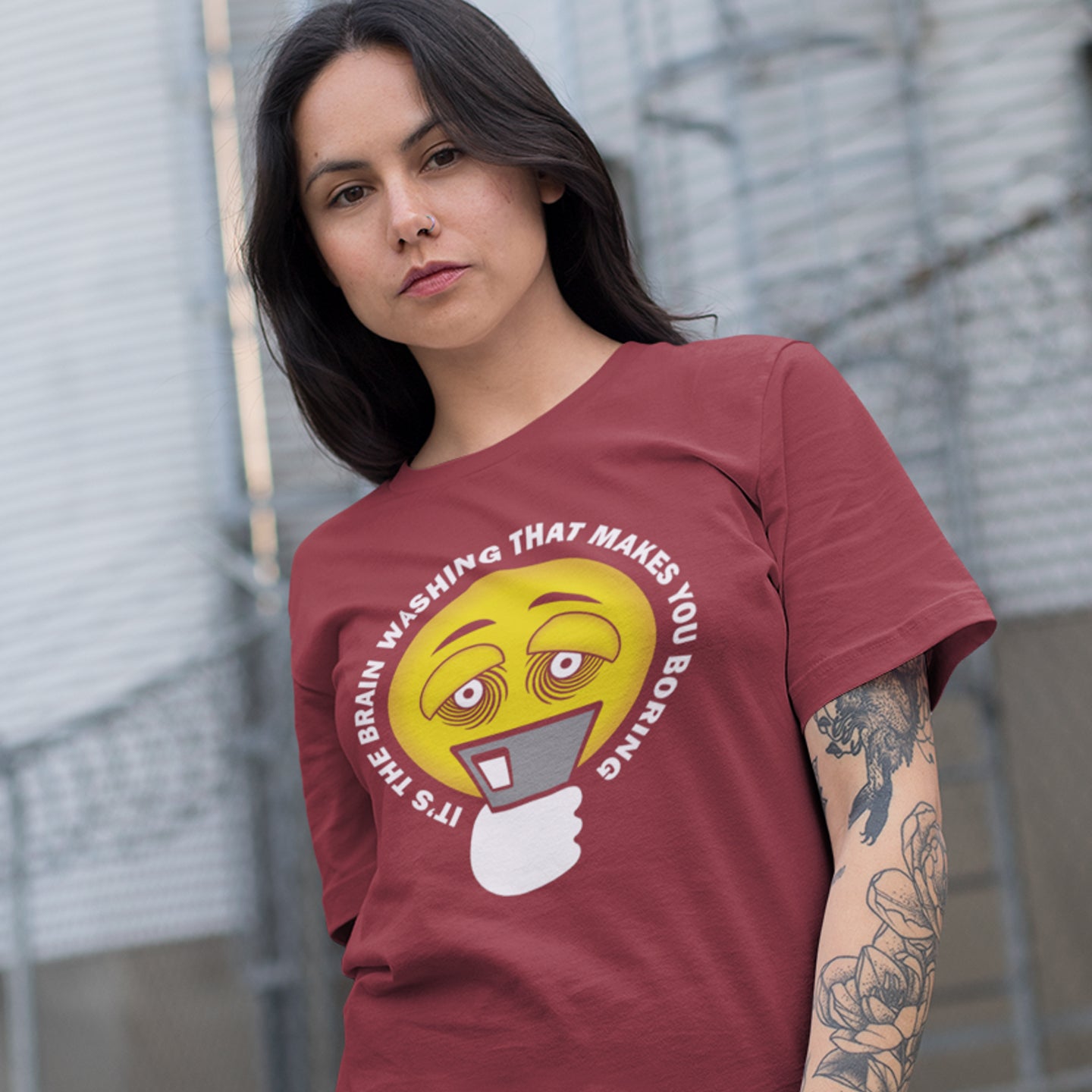 Woman wearing a red t-shirt with a graphic design and text. This cool graphic t-shirt highlights the hypnotic obsession some people have with their phone and suggests a conspiracy theory of brain washing as a cause. Ideal for displaying that anti smart phone feeling. Made from 100% organic ring-spun cotton, this conspiracy theory t-shirt is unisex, high-quality, super comfy, and best of all, eco-friendly.