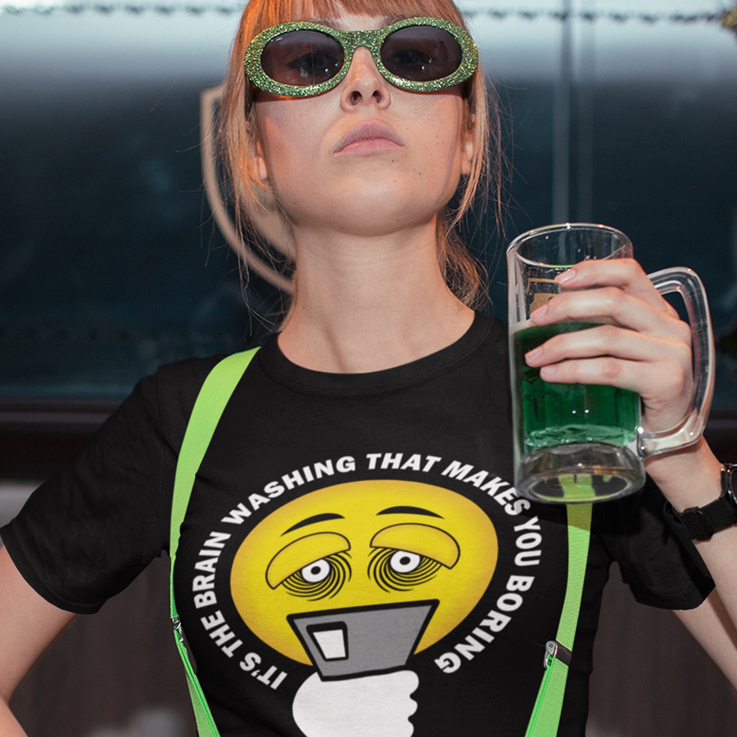 Person wearing a black t-shirt with a graphic design and holding a glass of green liquid. This cool graphic t-shirt highlights the hypnotic obsession some people have with their phone and suggests a conspiracy theory of brain washing as a cause. Ideal for displaying that anti smart phone feeling. Made from 100% organic ring-spun cotton, this conspiracy theory t-shirt is unisex, high-quality, super comfy, and best of all, eco-friendly.