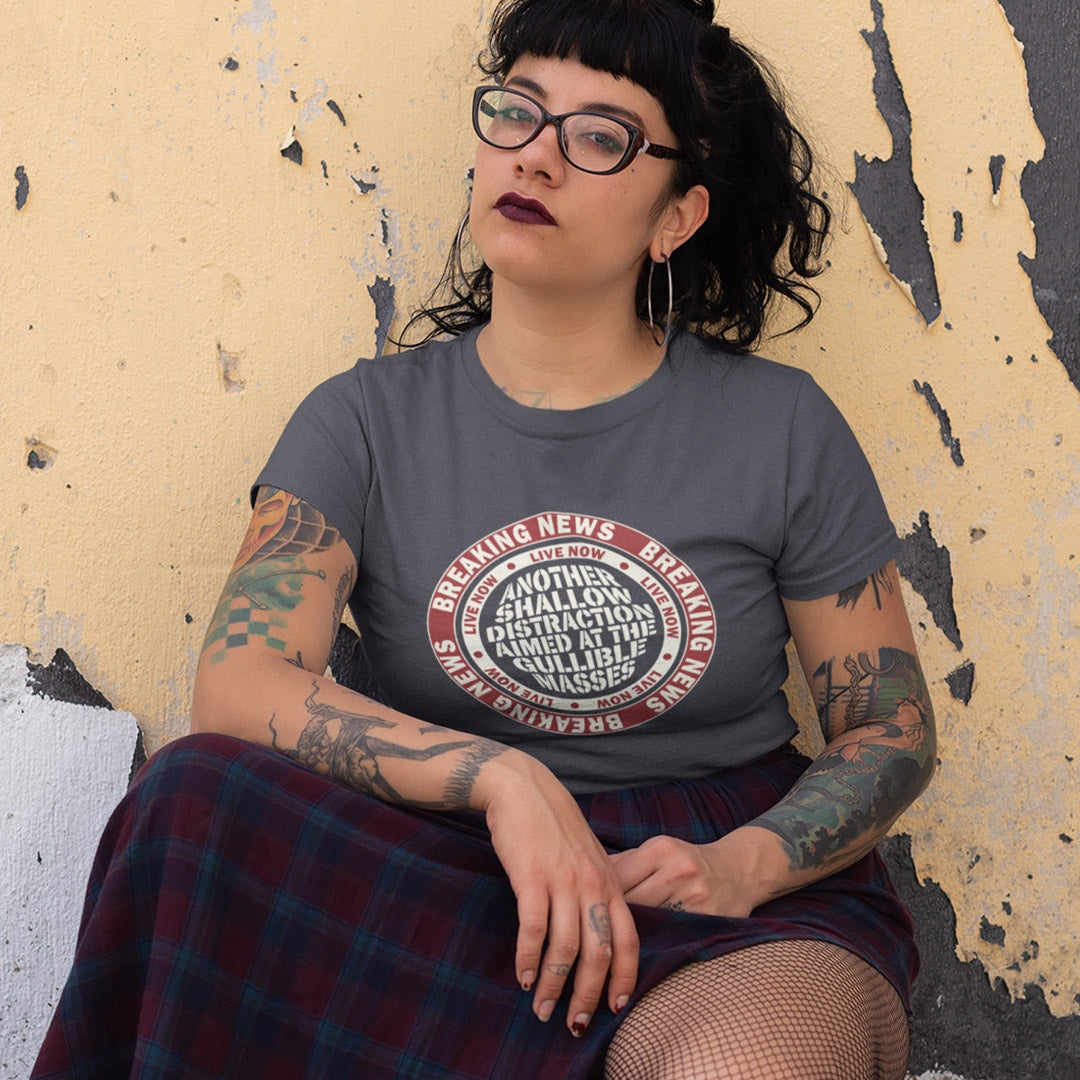 Woman crouched against a wall wearing an anthracite t shirt. An anti media, non conformist t shirt. This design suggests that the media is being used to keep us distracted from the real issues taking place around us. Don't fall for the new bright flashing lights! Made from 100% organic ring-spun cotton, this social awareness t shirt is unisex, high-quality, super comfy, and best of all, eco-friendly.