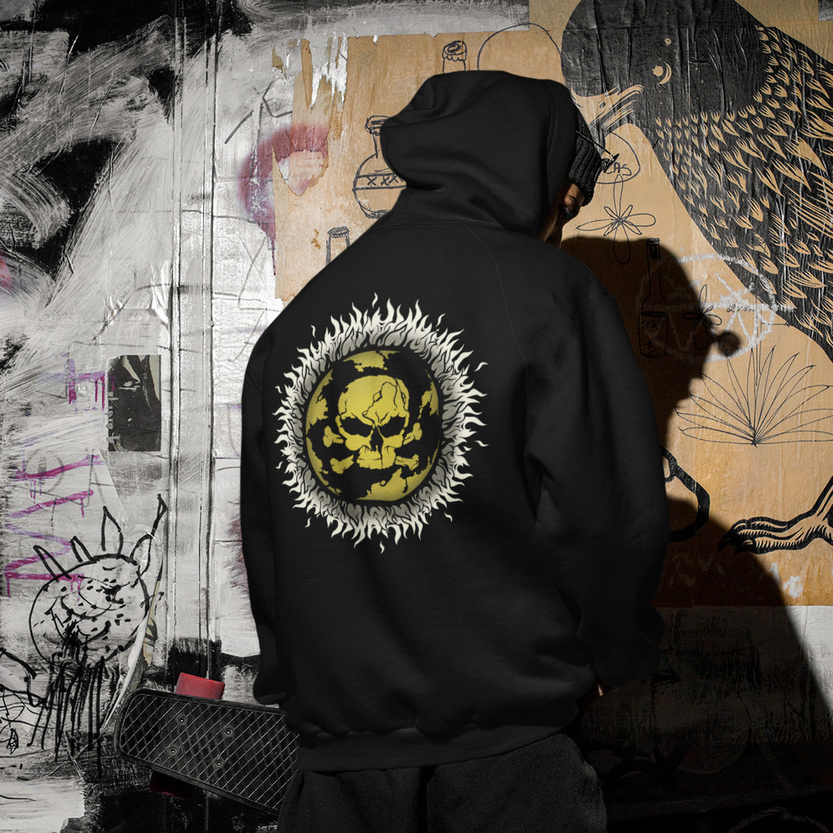 Person wearing a black hoodie with a yellow and white design on the back, standing in front of a graffiti-covered wall. This environmental hoodie is concerned with global warming. A design to keep climate issues at the forefront of peoples minds. A burning issue. Made from 100% organic ring-spun cotton, this environmental awareness hoodie is unisex, high-quality, super comfy, and best of all, eco-friendly.
