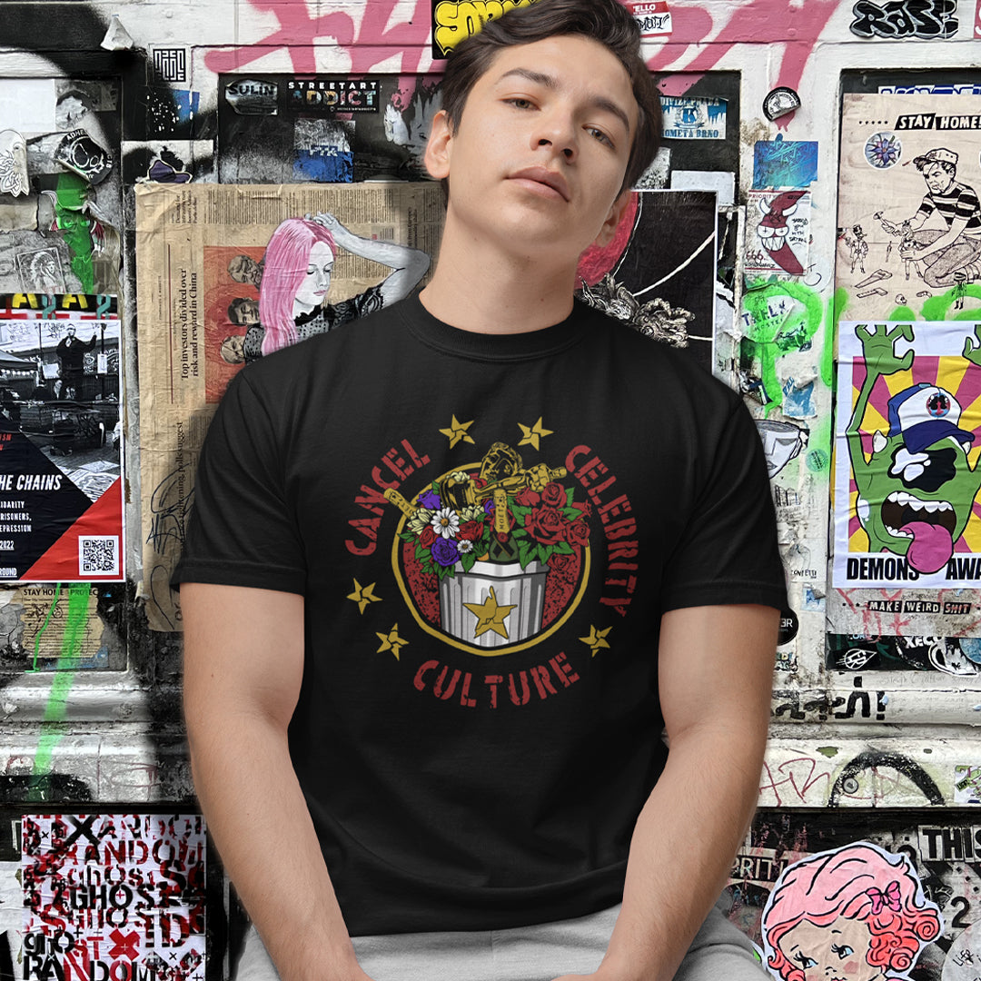 A young man wearing a black graphic t-shirt with a 'Cancel Celebrity Culture' print, posed against a graffiti-covered wall.