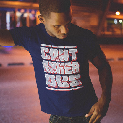 Man wearing a French navy blue t-shirt with red and white text, standing in an urban setting at night. A grumpy non conformist t shirt design. Argumentative and pessimistic ? Exercise your disapproval, and be proud to be labelled cantankerous. Made from 100% organic ring-spun cotton, this urban art t shirt is unisex, high-quality, super comfy, and best of all, eco-friendly.