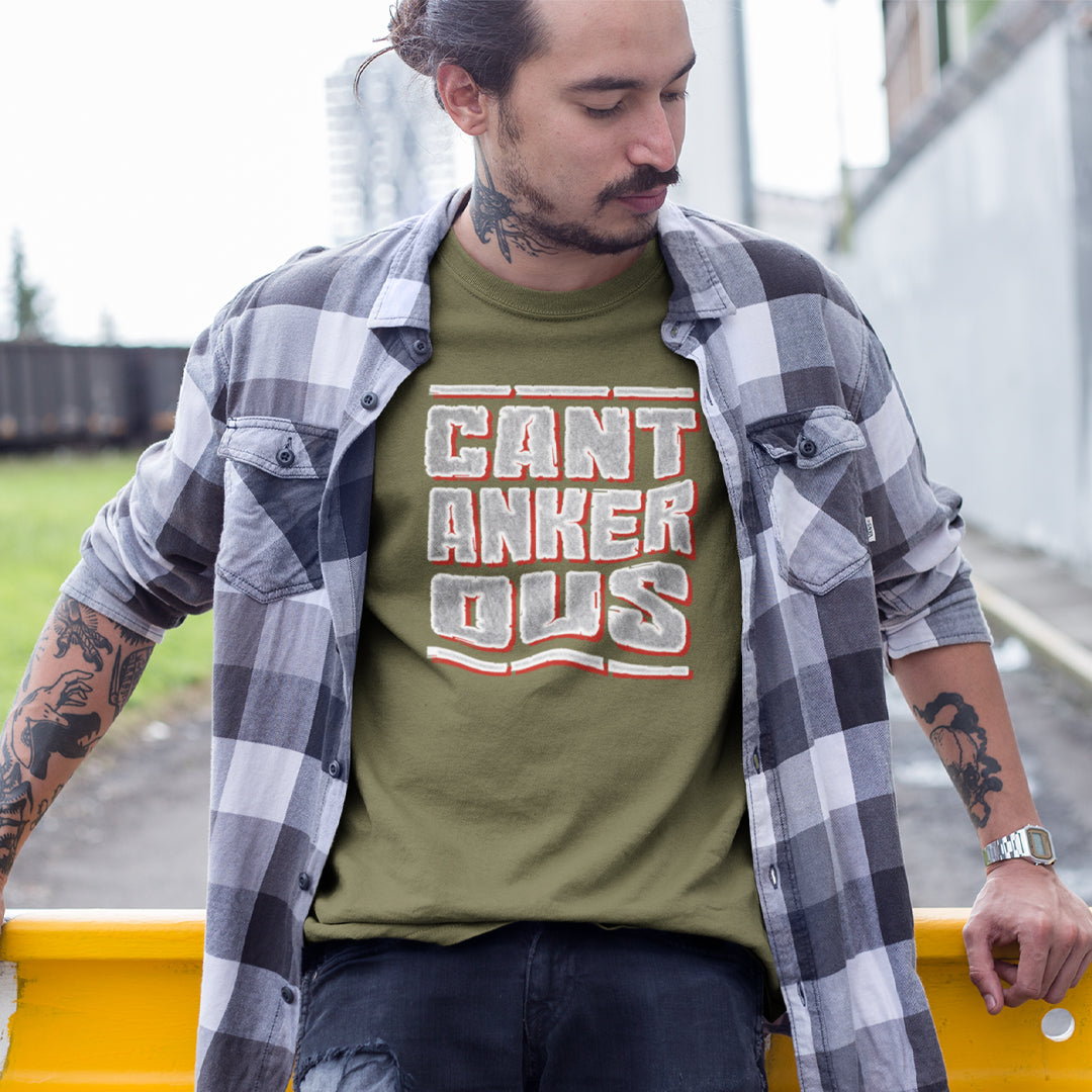 A man outside sitting on a fence wearing a khaki with a "CANTANKEROUS" logo.
