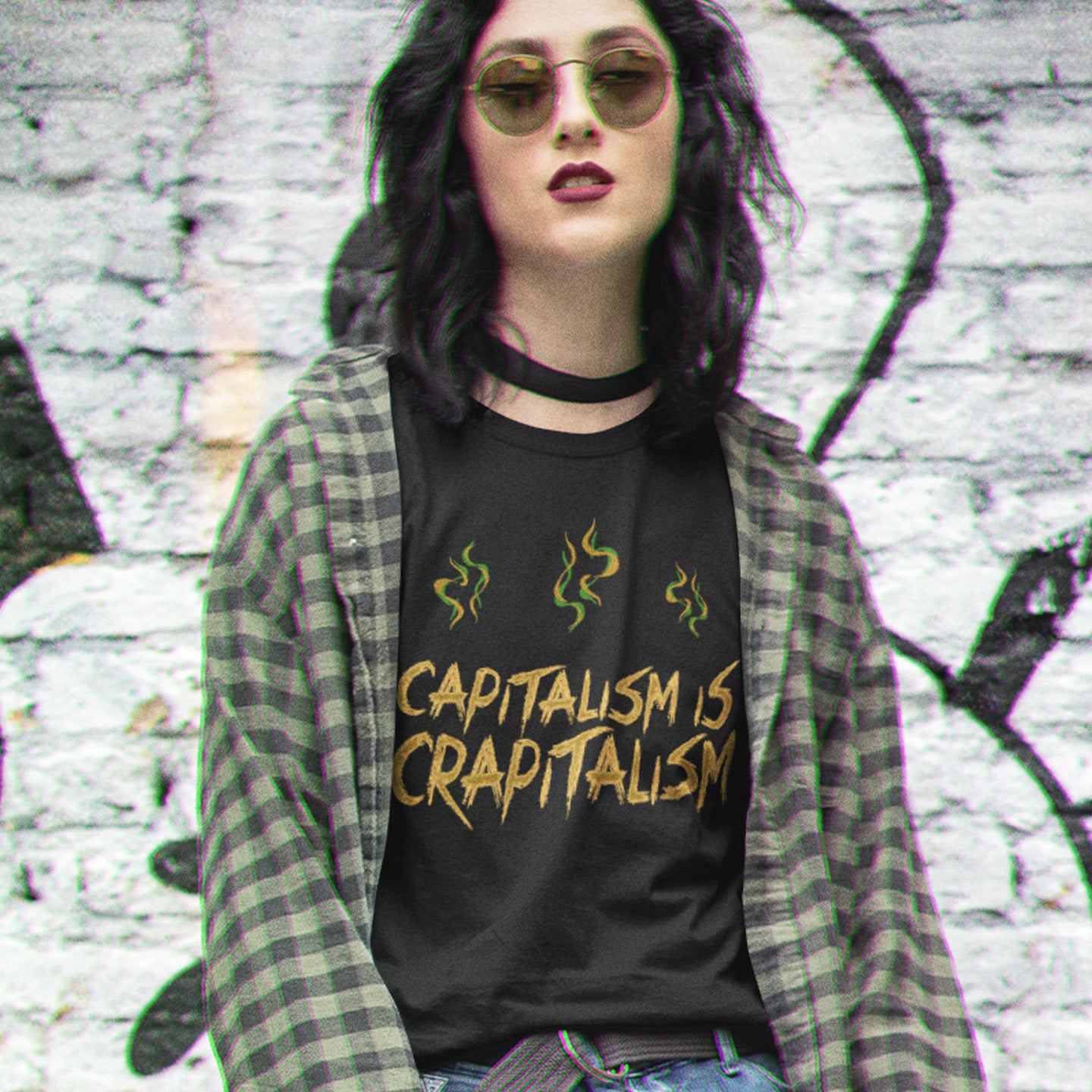 Person wearing a black t-shirt with 'CAPITALISM IS CRAPITALISM' text and plaid jacket against a graffiti-covered wall. A funny anti-capitalism t-shirt suggesting a letter was left out of the naming of capitalism. This unique anti-establishment t-shirt design argues that the system is crap. Made from 100% organic ring-spun cotton, this anti-capitalist t-shirt is unisex, high-quality, super comfy, and best of all, eco-friendly.