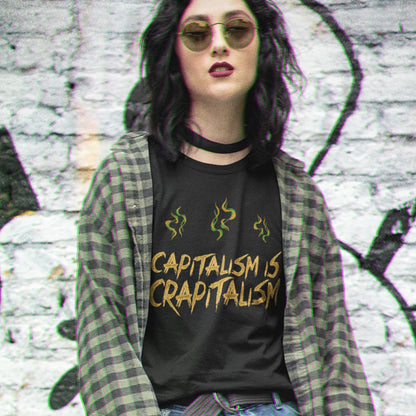 Person wearing a black t-shirt with 'CAPITALISM IS CRAPITALISM' text and plaid jacket against a graffiti-covered wall. A funny anti-capitalism t-shirt suggesting a letter was left out of the naming of capitalism. This unique anti-establishment t-shirt design argues that the system is crap. Made from 100% organic ring-spun cotton, this anti-capitalist t-shirt is unisex, high-quality, super comfy, and best of all, eco-friendly.