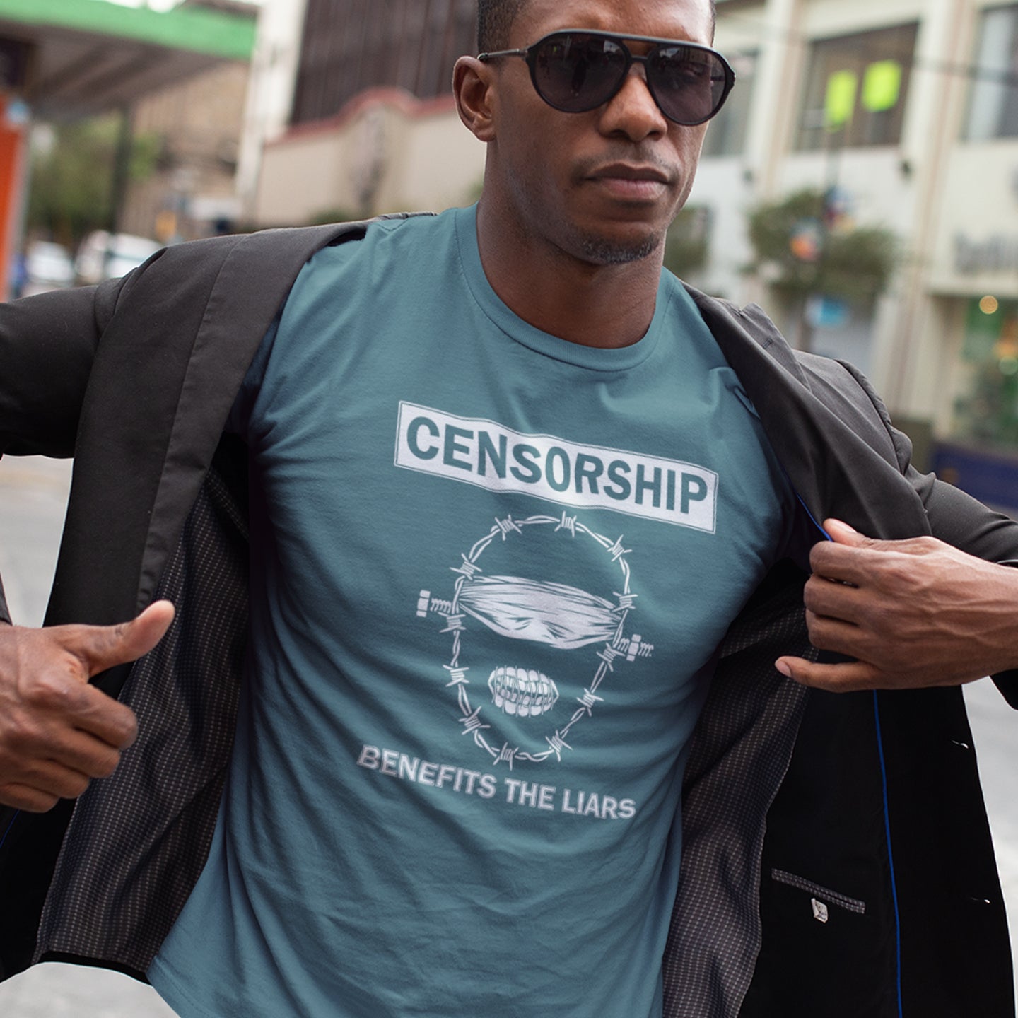 Man wearing a stargazer t-shirt with text and graphics, standing outdoors. This political t-shirt highlights the benefits of censorship. Lies and censorship go hand-in-hand as tools of control and manipulation. This unique design promotes social awareness and freedom of speech. Made from 100% organic ring-spun cotton, this political t-shirt is unisex, high-quality, super comfy, and best of all, eco-friendly.