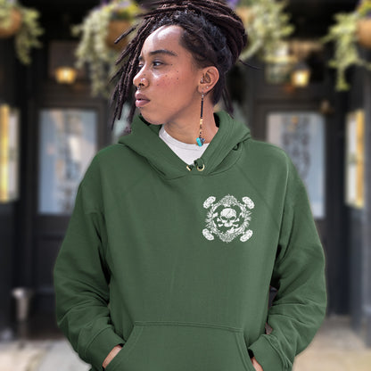 Person wearing a green hoodie with a white design, standing in an outdoor setting. A 'save the planet' hoodie about human impact on nature. An Earth day special. This design highlights the amount of death and destruction we create as a species. Comfortable and practical. It's extra soft and has a convenient front pouch pocket. Made from organic cotton and recycled polyester, this anti-war political hoodie is a great eco-friendly choice.