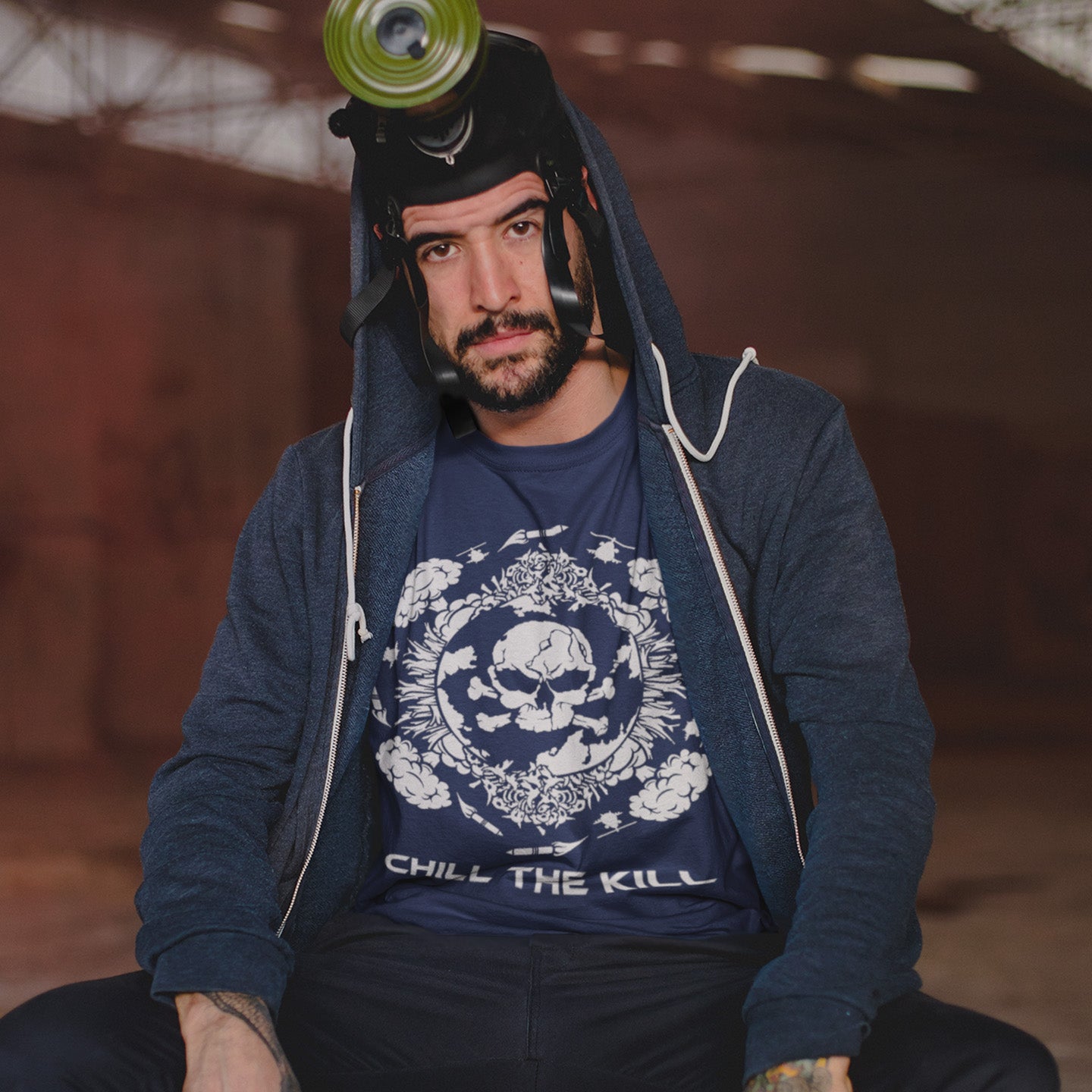 Man wearing a blue hoodie sitting against a blurred background. An original save the planet t-shirt. A unique creation in a series of designs about environmental issues and climate concern. This one highlighting the amount of death and destruction we create as a species. Express your counterculture alternative view and encourage social awareness. Made from 100% organic ring-spun cotton, this political t-shirt is unisex, high-quality, super comfy, and best of all, eco-friendly.