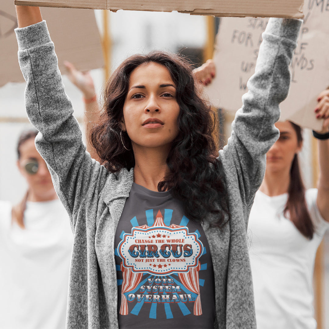 Woman holding a cardboard sign with a protest or rally setting. This anti government t shirt points out that you can change the clowns but the circus remains. Does it matter who fronts a corrupt system? The whole circus needs to go. Made from 100% organic ring-spun cotton, this civil rights t shirt is unisex, high-quality, super comfy, and best of all, eco-friendly.