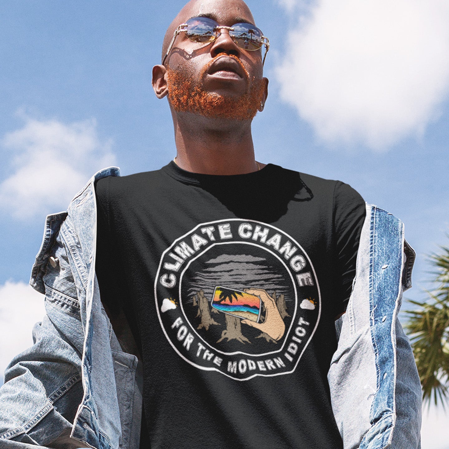 Man wearing a black t-shirt with a climate change graphic and text outdoors. A satirical save the planet t-shirt exposing the denial still opposing a very serious issue. In this age of smart technology it's surprising there isn't an app that helps us ignore the climate crisis. Satire at it's best. Made from 100% organic ring-spun cotton, this social awareness t-shirt is unisex, high-quality, super comfy, and best of all, eco-friendly.