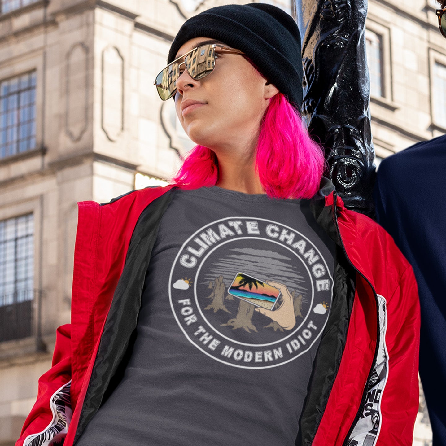 Person wearing a 'Climate Change for the Modern Idiot' t-shirt with a red jacket and black hat, standing in front of a building. A satirical save the planet t-shirt exposing the denial still opposing a very serious issue. In this age of smart technology it's surprising there isn't an app that helps us ignore the environmental crisis. Satire at it's best. Made from 100% organic ring-spun cotton, this save the world t shirt is unisex, high-quality, super comfy, and best of all, eco-friendly.