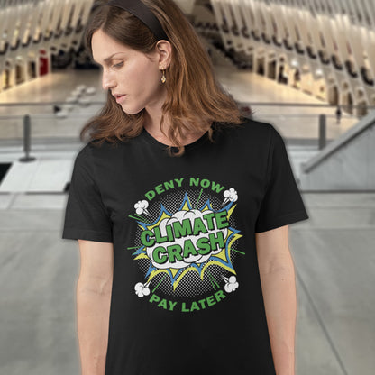 A woman standing in a shopping centre wearing a black short sleeved crew neck t-shirt with a pop art design in white and green, text saying "CLIMATE CRASH, DENY NOW PAY LATER".